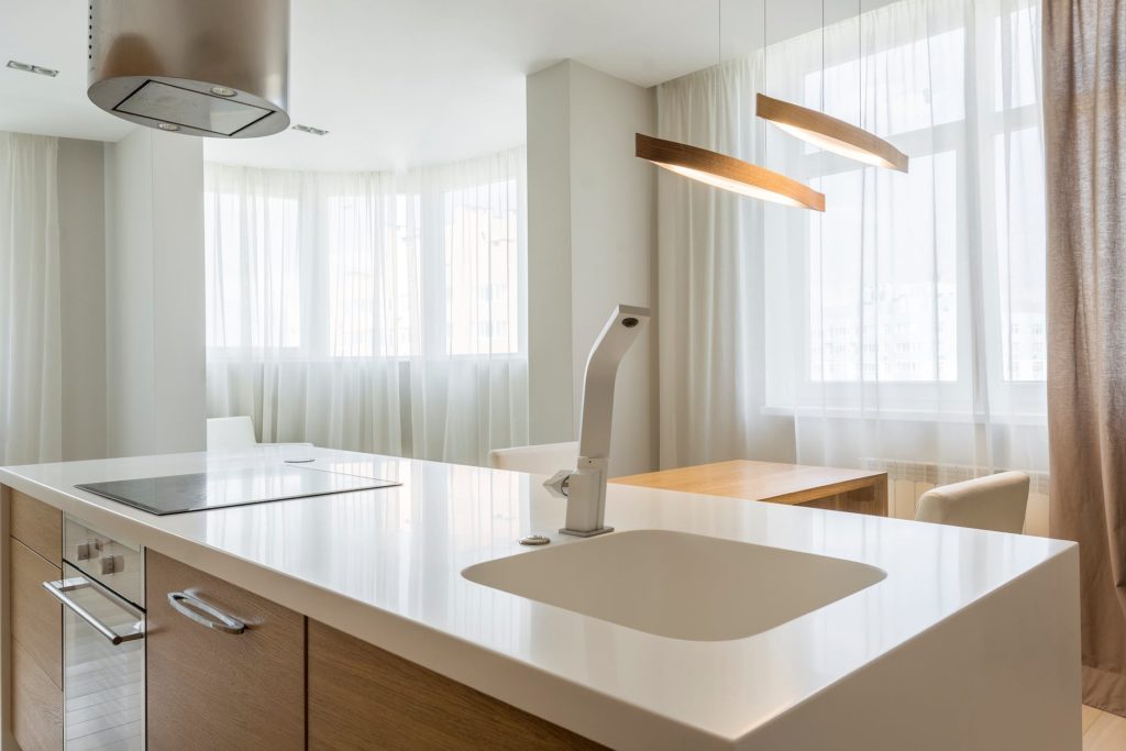 kitchen counter and sink facing the windows with sheer curtains